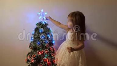 孩子在节日树上检查一颗圣诞星。 小女孩在孩子们的房间里靠近圣诞树`玩耍